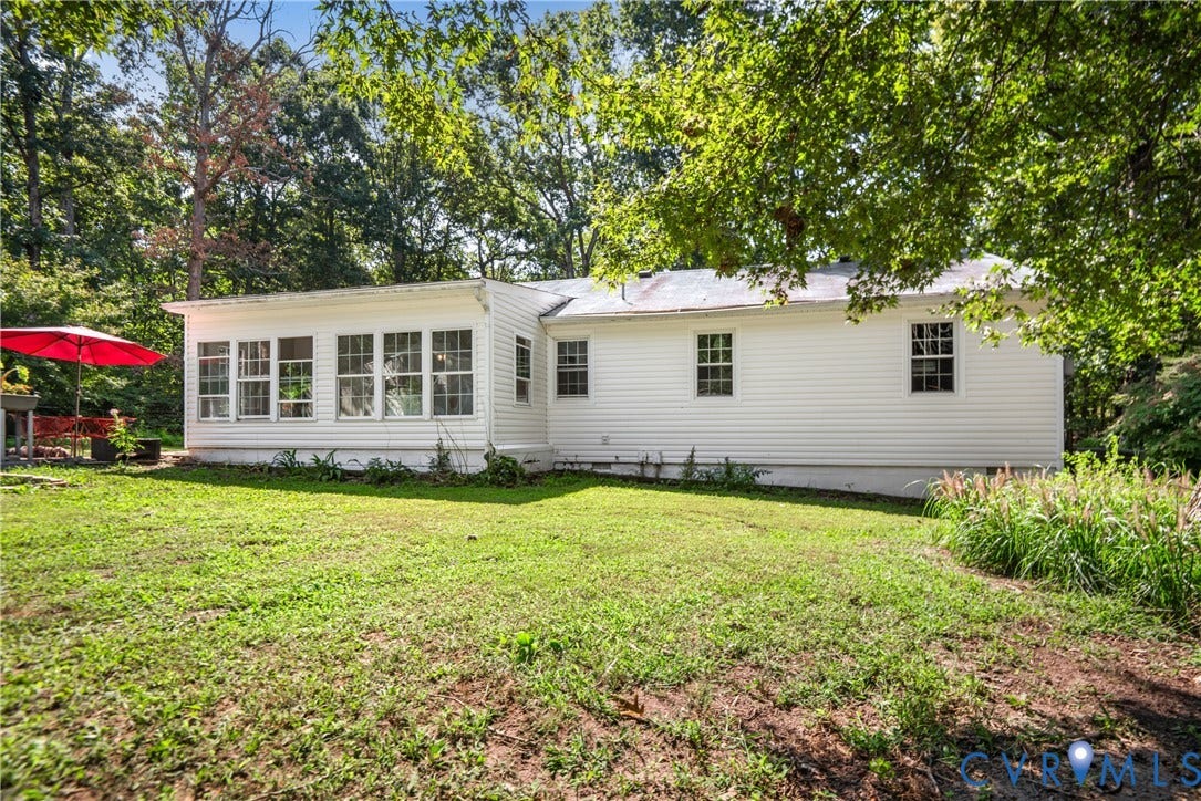 3940 Three Bridge Road, Powhatan, VA 23139 Expansive backyard featuring a manicured lawn, established landscaping, white siding, and a sunroom with multiple windows