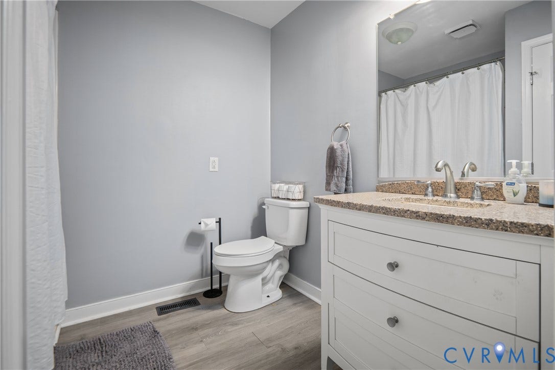 3940 Three Bridge Road, Powhatan, VA 23139 White vanity with drawer storage, integrated sink, brushed nickel faucet, large mirror, and wood-finish flooring