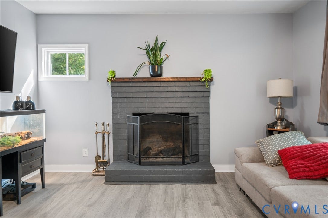 3940 Three Bridge Road, Powhatan, VA 23139 Painted brick fireplace with a wood mantel, wood-finish flooring, and white trim