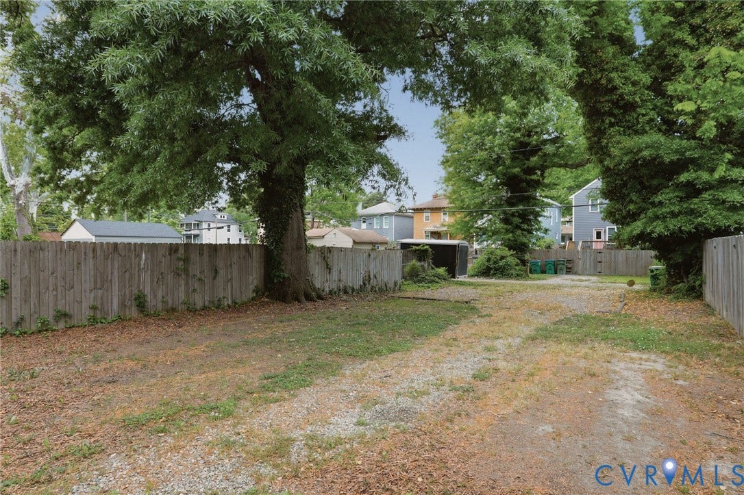 3110 3rd Avenue, North Highland Park, Richmond, VA 23222 Expansive backyard featuring a gravel-surfaced area, a mature tree providing natural shade, and wood privacy fencing