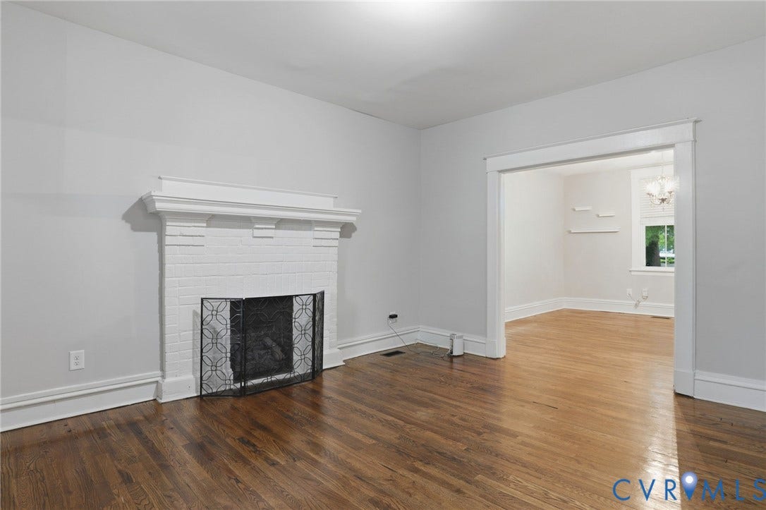 3110 3rd Avenue, North Highland Park, Richmond, VA 23222 Interior living space showcasing a prominent white brick fireplace with a decorative mantel and a black metal fire screen