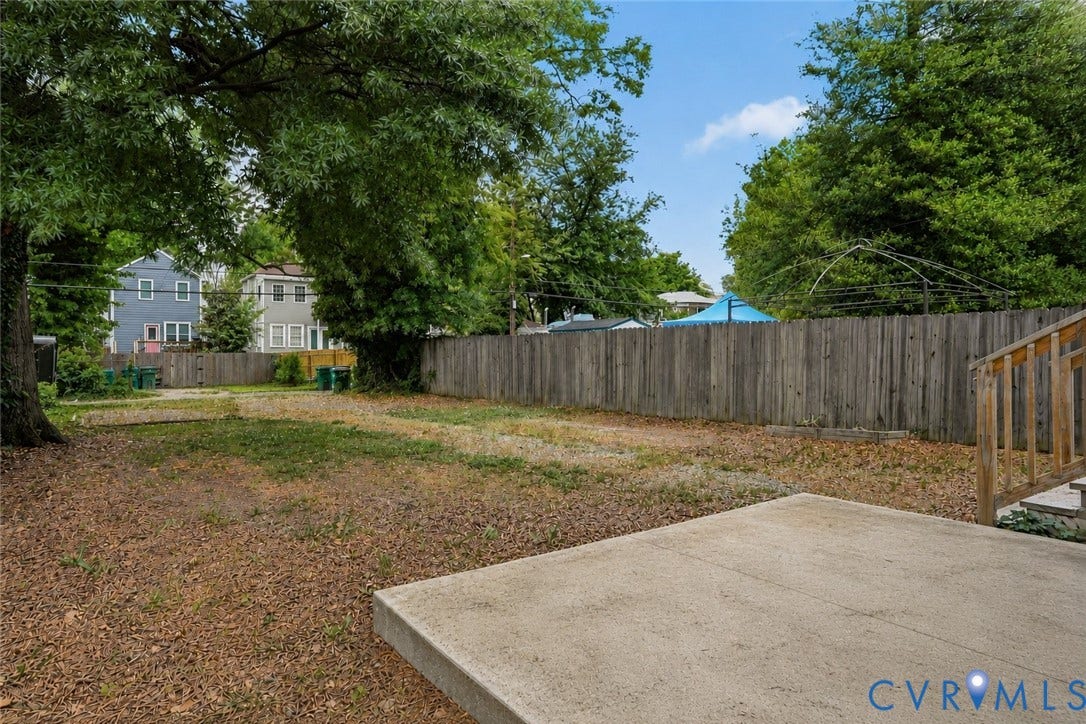 3110 3rd Avenue, North Highland Park, Richmond, VA 23222 Expansive backyard featuring a concrete patio, wood privacy fencing, mature trees, and a grassy area