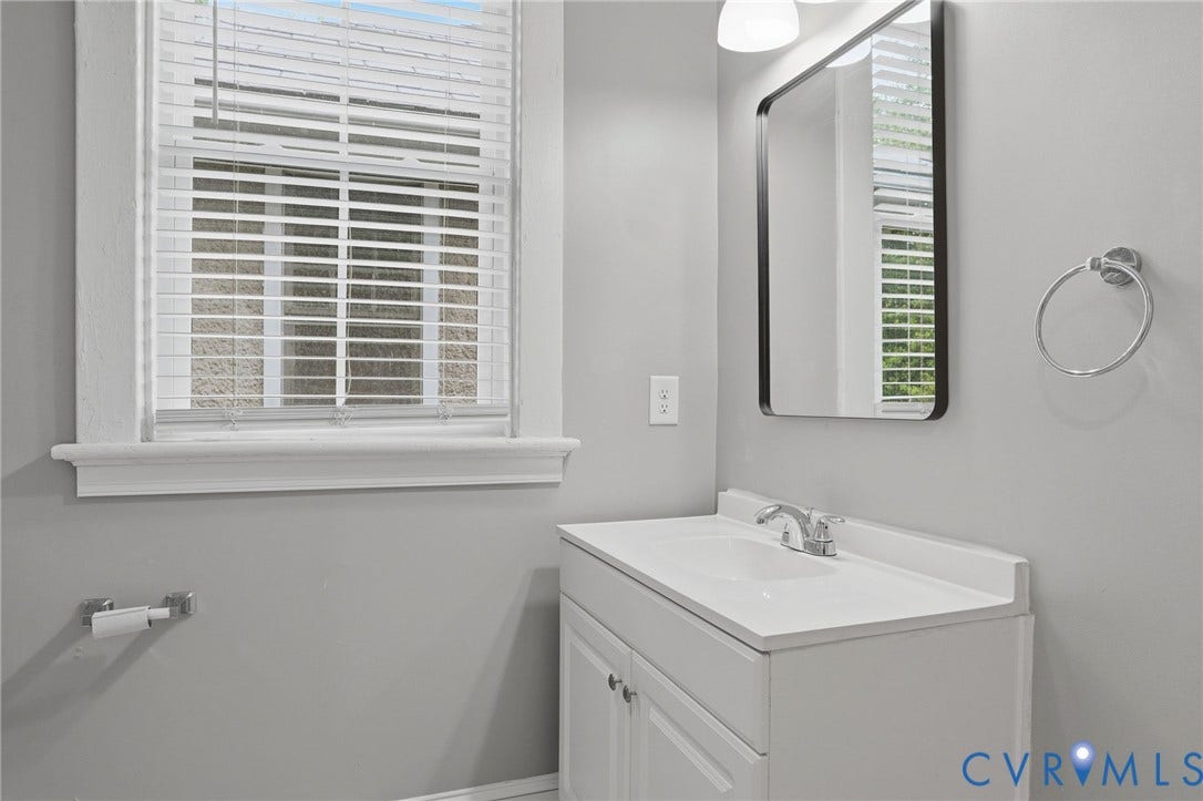 3110 3rd Avenue, North Highland Park, Richmond, VA 23222 Bathroom vanity with a white countertop and integrated sink, chrome faucet, and a wall-mounted rectangular mirror with a black frame