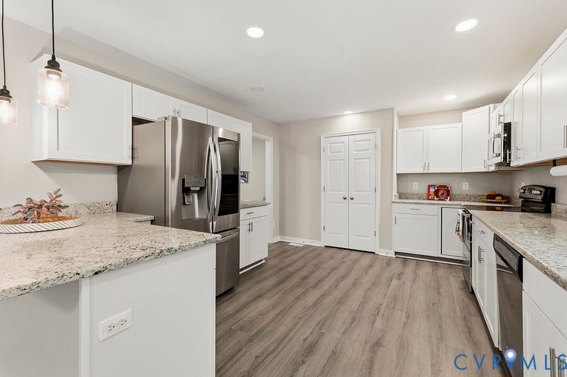 9007 Chatham Grove Lane, Richmond, VA 23236 Kitchen featuring white cabinetry, light-toned countertops, stainless steel appliances, and wood-finish flooring