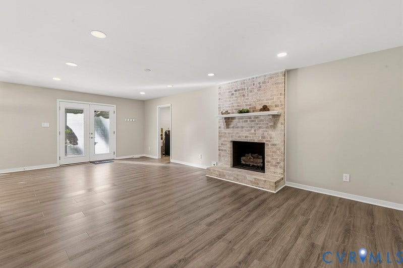 9007 Chatham Grove Lane, Richmond, VA 23236 Spacious room featuring wood-finish flooring, a brick fireplace with mantel, recessed lighting, and white French doors