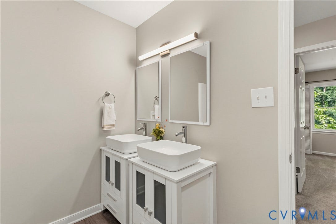 9007 Chatham Grove Lane, Richmond, VA 23236 Dual vessel sinks set atop white vanities with cabinet storage, individual framed mirrors, and a shared linear light fixture
