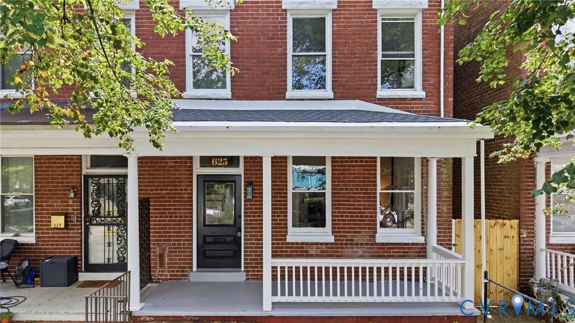 625 N 33rd Street, Chimborazo, Richmond, VA 23223 Classic brick Colonial featuring a welcoming front porch with white railings and columns, black-framed entry door with decorative glass panel, and large multi-pane windows
