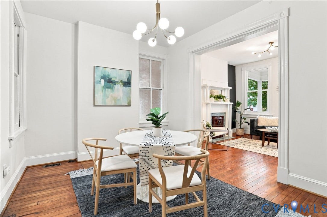 625 N 33rd Street, Chimborazo, Richmond, VA 23223 Elegant dining room showcasing warm wood-finish flooring, a round pedestal table, natural light from multiple doorways, and a modern chandelier with brass and frosted glass accents