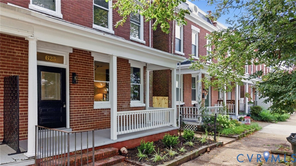 625 N 33rd Street, Chimborazo, Richmond, VA 23223 Brick exterior featuring a covered front porch with white railings, a dark entry door with transom window, and ground-level landscaping