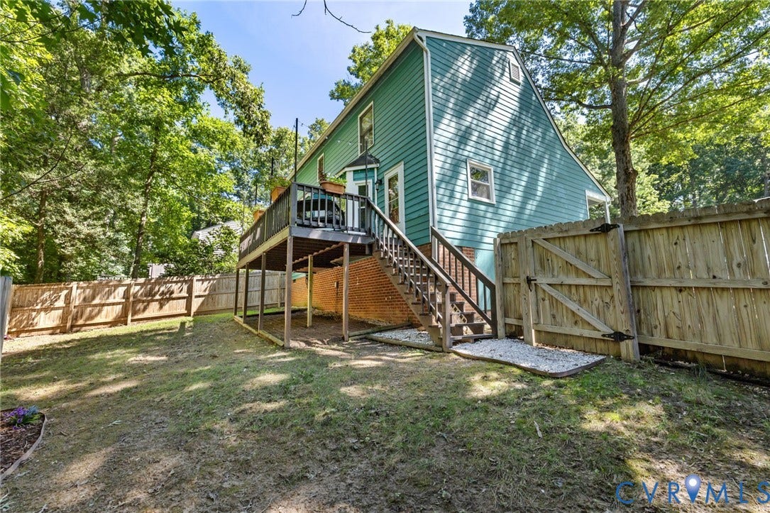 7306 Native Dancer Drive, Midlothian, VA 23112 Expansive backyard with a wooden fence, featuring a multi-level deck, a wooden staircase, and brick foundation elements