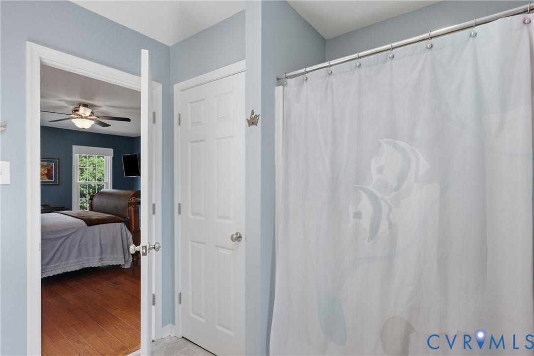 Ensuite bathroom featuring soft blue-gray walls, a linen closet and a shower/tub combo