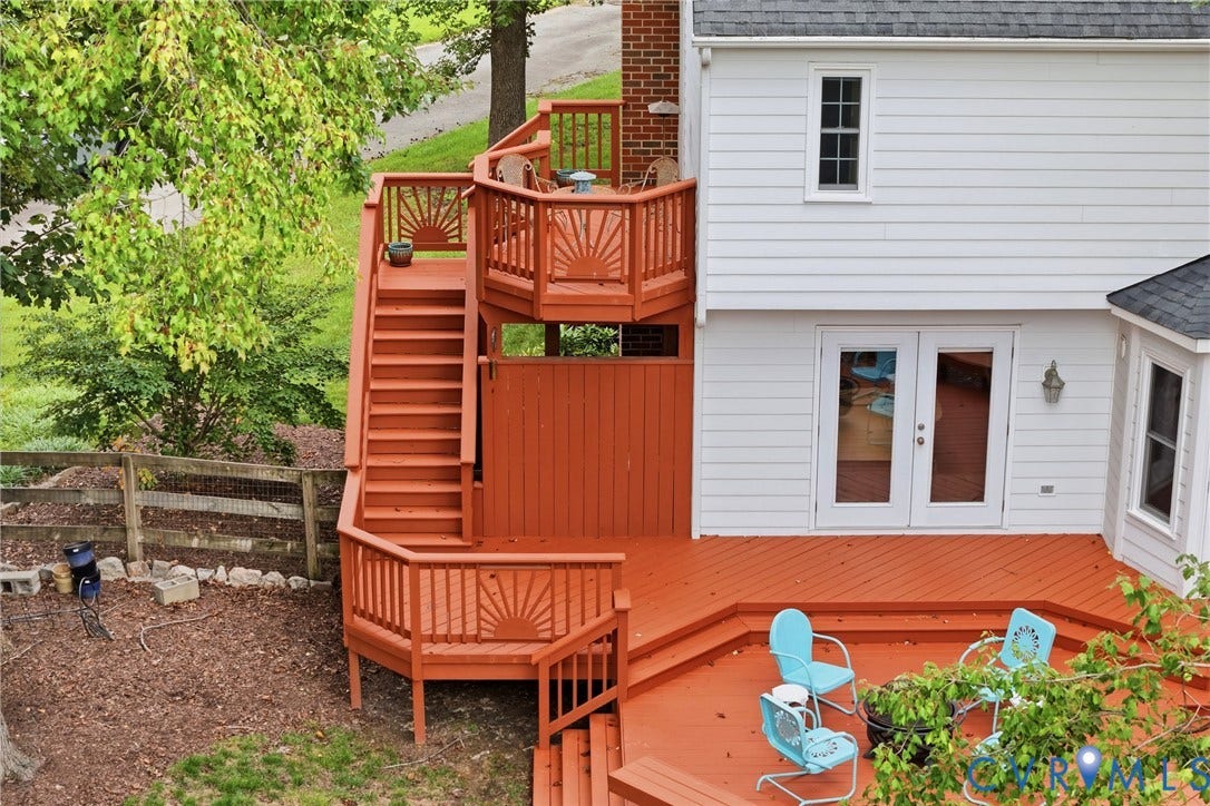Expansive composite deck featuring multiple tiers with rust-red wood-finish railings, decorative spindle details, and built-in seating areas