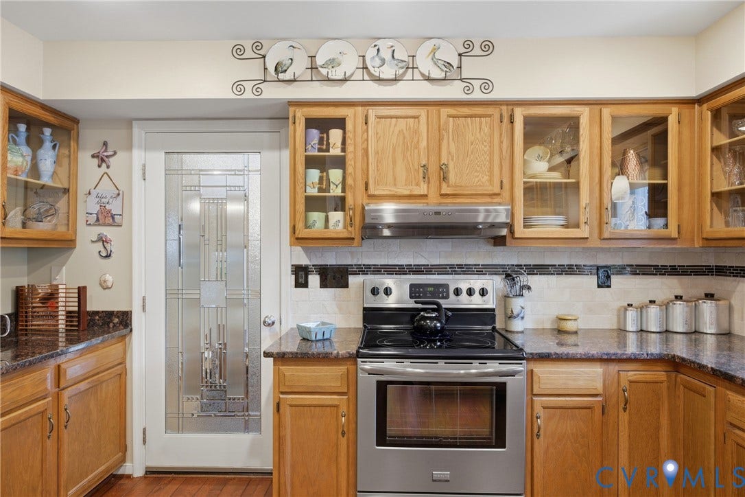 Kitchen with warm wood cabinetry and dark countertops
