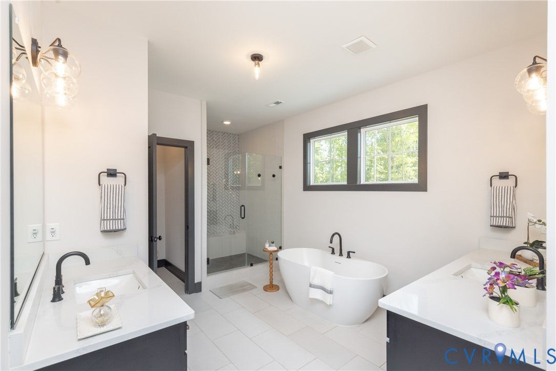 4600 Otter Court, Moseley, VA 23120 Spacious bathroom featuring a freestanding soaking tub, dual vanities with white countertops, a glass-enclosed shower with a tiled surround, and white tile flooring