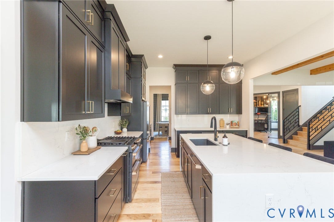 4600 Otter Court, Moseley, VA 23120 Open-concept kitchen featuring an expansive island with seating, dark shaker cabinetry, light countertops, and wood-finish flooring
