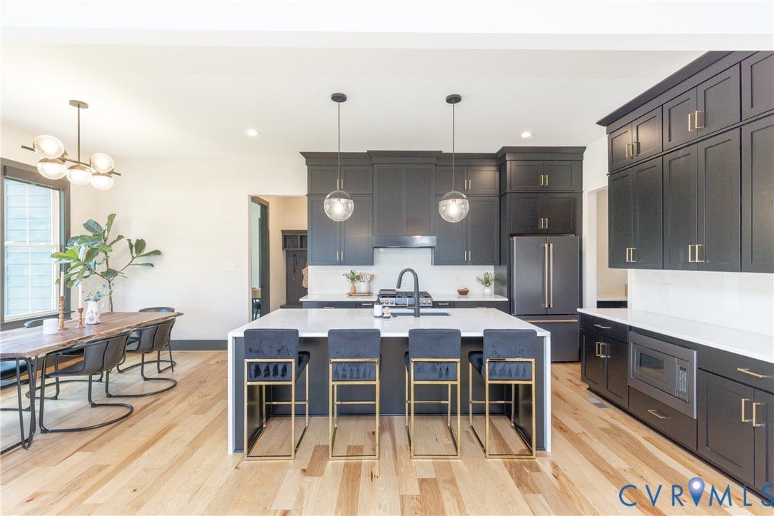 4600 Otter Court, Moseley, VA 23120 Expansive kitchen and dining area featuring light wood flooring, a large center island with a sink, pendant lighting, and abundant dark cabinetry with gold-tone hardware