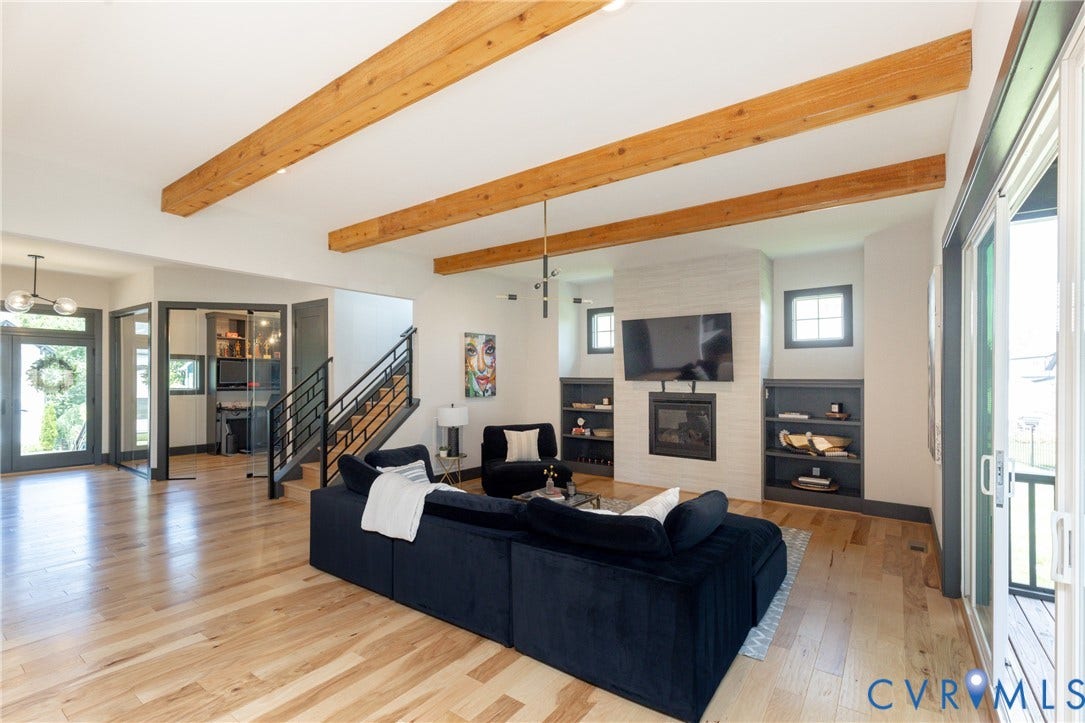 4600 Otter Court, Moseley, VA 23120 Spacious living area featuring wood-finish flooring, exposed ceiling beams, a tile fireplace surround, and built-in shelving