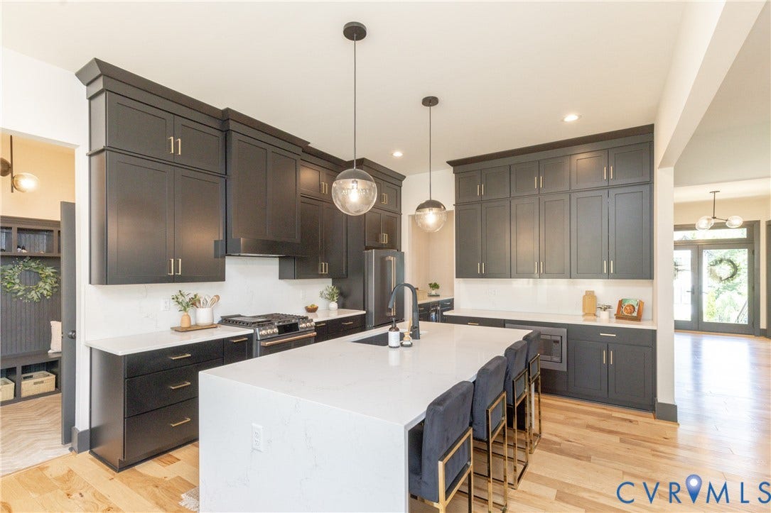 4600 Otter Court, Moseley, VA 23120 Contemporary kitchen featuring dark cabinetry, light countertops, wood-finish flooring, a central island with seating, and pendant lighting