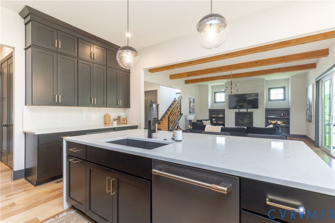 4600 Otter Court, Moseley, VA 23120 Open-concept kitchen and living area featuring dark cabinetry, light quartz countertops, a kitchen island with an undermount sink, pendant lighting, and exposed ceiling beams