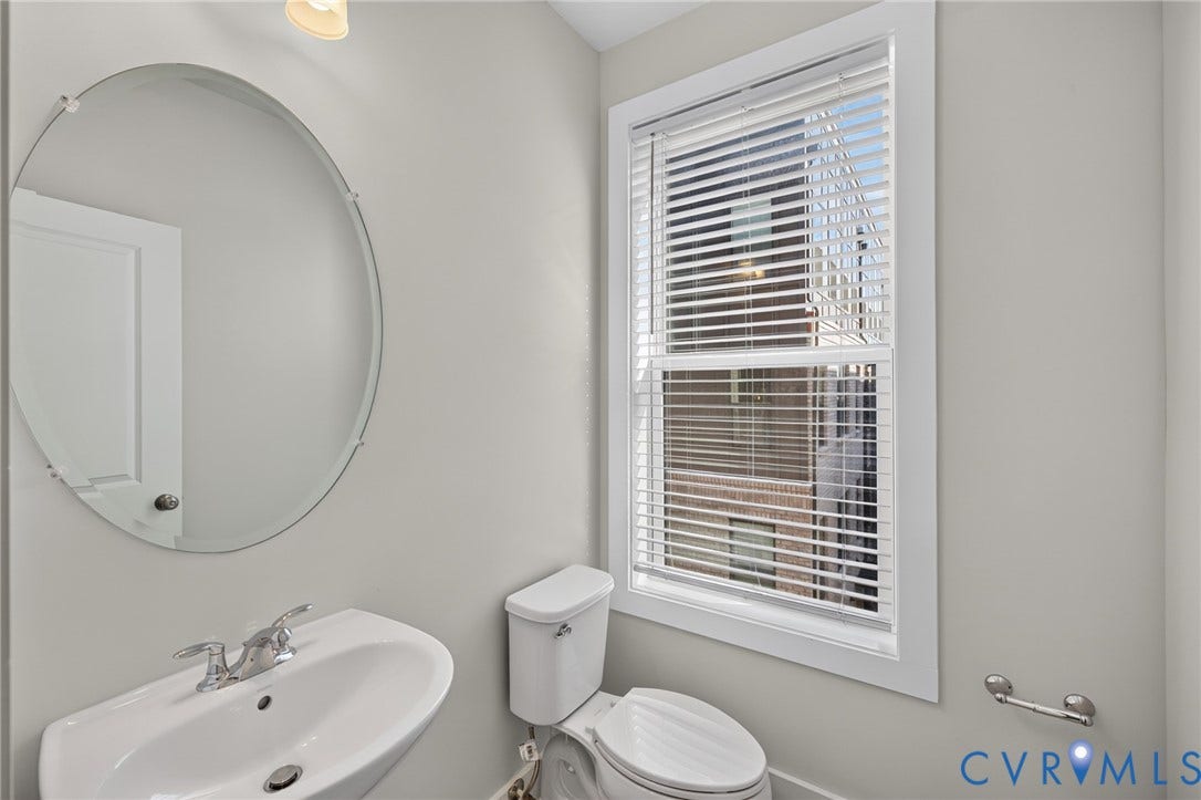 1509 Moore Street, #B, Richmond, VA 23220 Pedestal sink with chrome fixtures, oval frameless mirror, and window with horizontal blinds