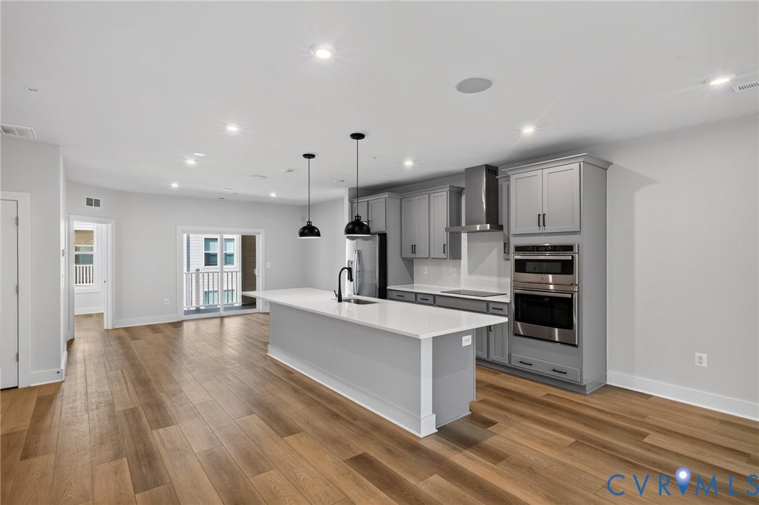 1509 Moore Street, #B, Richmond, VA 23220 Spacious kitchen featuring an island with a white countertop, grey cabinetry, stainless steel appliances, and wood-finish flooring