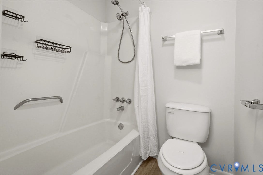 2903 Fox Chase Drive, Huntsbridge, Midlothian, VA 23112 Clean and functional bathroom featuring a white porcelain toilet with elongated bowl, ceramic tile surround with grab bar accessibility, chrome shower fixtures with handheld showerhead, white subway tile walls, and chrome towel bar and shelving