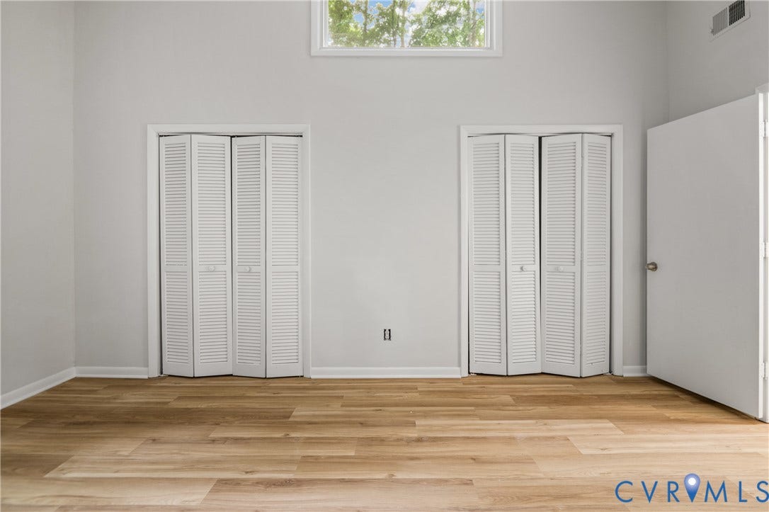 2903 Fox Chase Drive, Huntsbridge, Midlothian, VA 23112 Spacious bedroom featuring gleaming wood-finish flooring, abundant natural light from transom window, and two sets of louvered bifold closet doors providing generous storage solutions