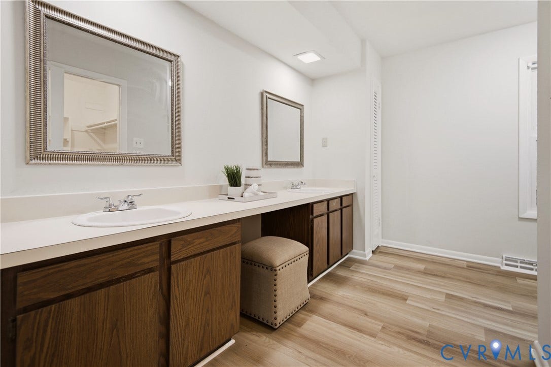 2903 Fox Chase Drive, Huntsbridge, Midlothian, VA 23112 Spa-inspired primary bathroom showcasing dual vanities with white quartz countertops, rich wood cabinetry with decorative hardware, and dual framed mirrors