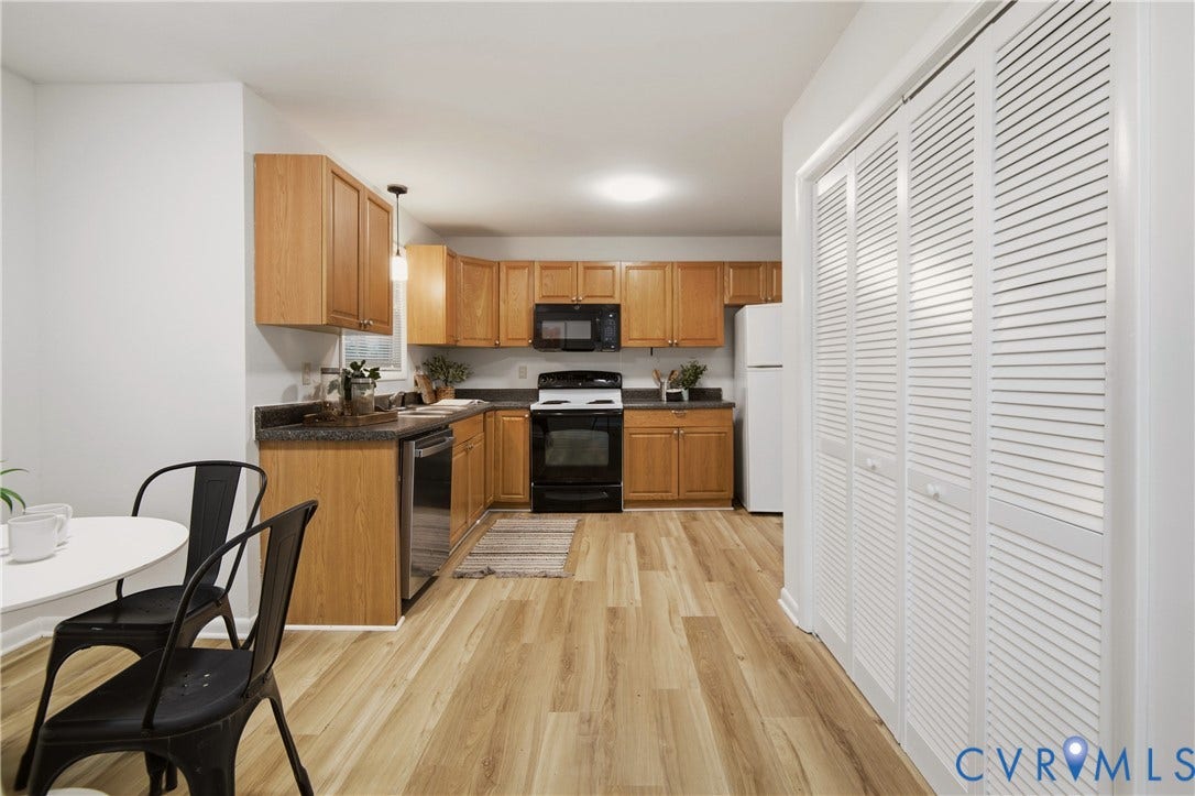 2903 Fox Chase Drive, Huntsbridge, Midlothian, VA 23112 Open-concept kitchen featuring wood-finish flooring, light wood cabinetry, dark countertops, and a full suite of black and stainless steel appliances