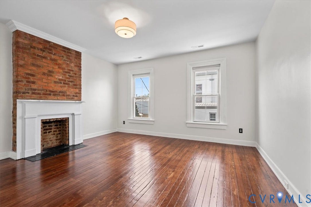 2510 E Leigh Street, Church Hill, Richmond, VA 23223 Exposed brick accent wall with a white mantel, hardwood flooring, and two double-hung windows