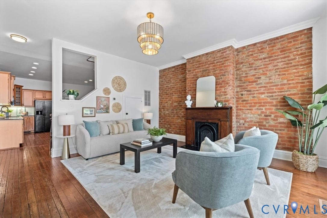 2510 E Leigh Street, Church Hill, Richmond, VA 23223 Exposed brick wall with a wood-mantel fireplace, hardwood flooring, and a tiered chandelier
