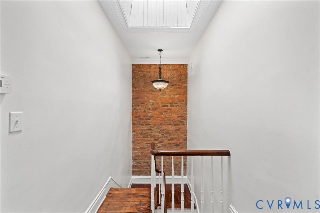 2510 E Leigh Street, Church Hill, Richmond, VA 23223 Exposed brick accent wall, wood-finish flooring, skylight, pendant light fixture, and white painted walls