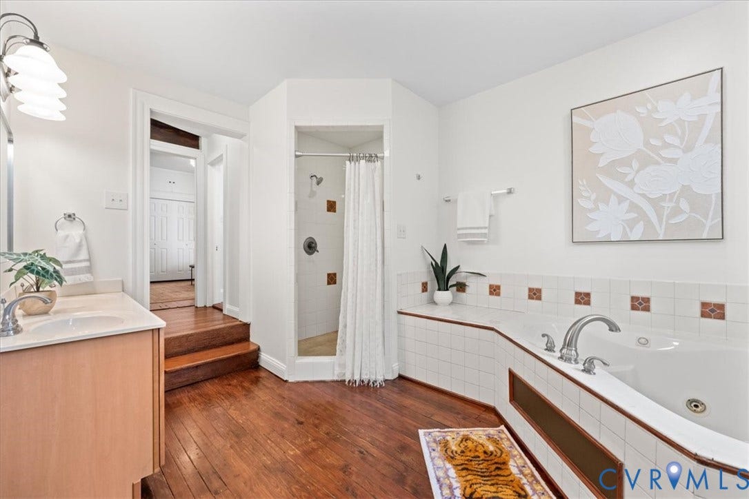 2510 E Leigh Street, Church Hill, Richmond, VA 23223 Hardwood flooring, built-in soaking tub, tiled shower enclosure, single vanity with integrated sink, and white wall tiling