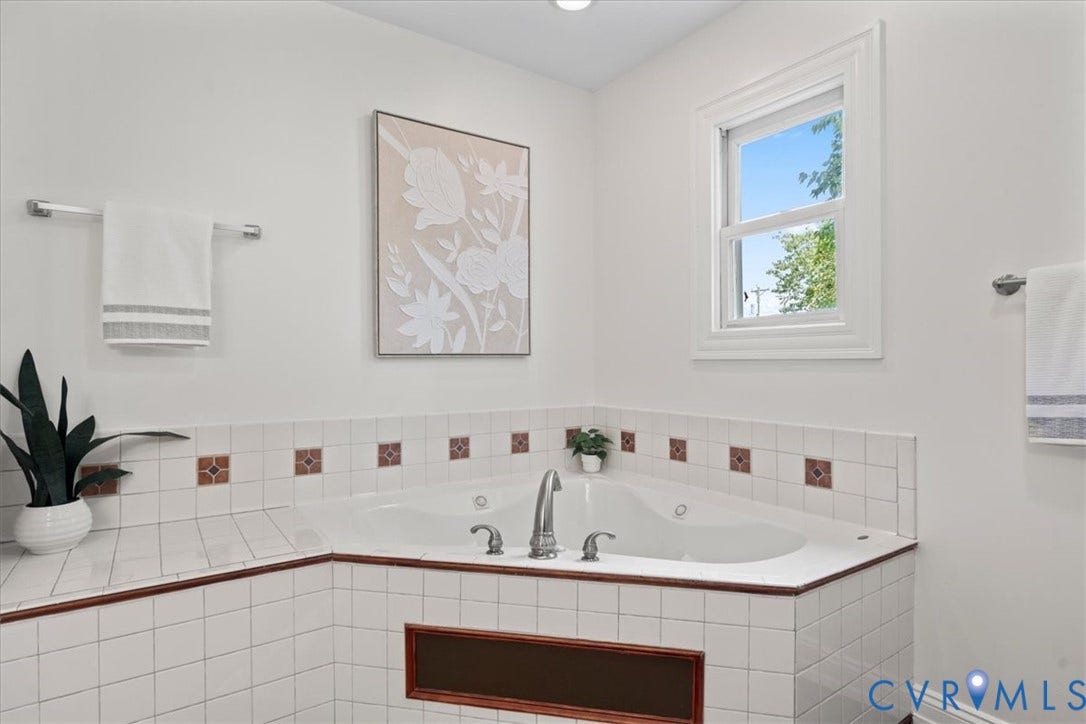 2510 E Leigh Street, Church Hill, Richmond, VA 23223 Corner soaking tub with a tiled surround, accent trim, and a double-hung window