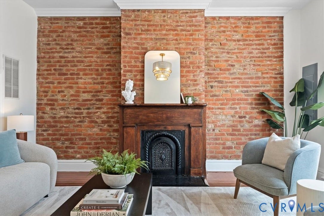 2510 E Leigh Street, Church Hill, Richmond, VA 23223 Exposed brick wall with crown molding, a wood-finish mantel, and a dark metal fireplace insert