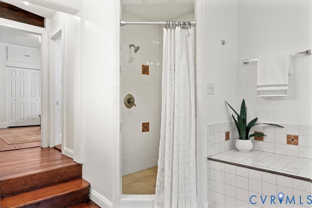 2510 E Leigh Street, Church Hill, Richmond, VA 23223 Tiled shower enclosure with bronze-finish fixtures, white wall tile, and accent tiles