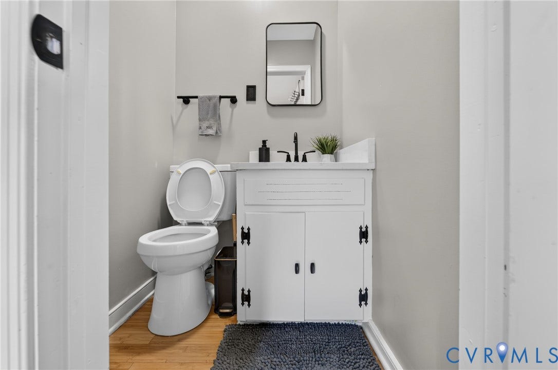3401 Austin Avenue, Brentwood, Henrico, VA 23222 Compact bathroom featuring a white vanity with black hardware, a rectangular mirror, and wood-finish flooring