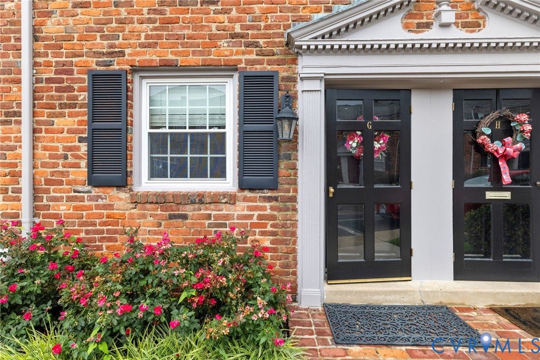 405 N Hamilton Street, #G, Richmond, VA 23221 Brick exterior featuring dark louvered shutters, a white-framed window, and a decorative architectural door surround