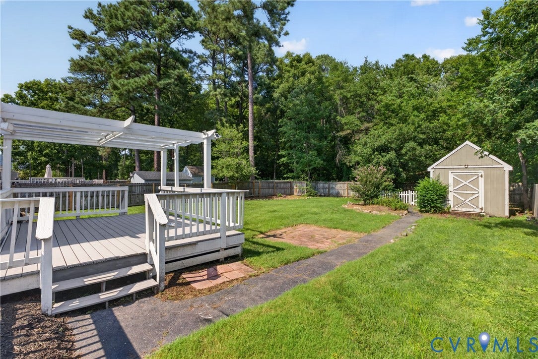 2020 Knotty Drive, Glen Allen, VA 23060 Expansive backyard oasis featuring a composite deck with pergola and seating area, manicured lawn, mature tree canopy, paved pathway, and detached storage shed with peaked roof design