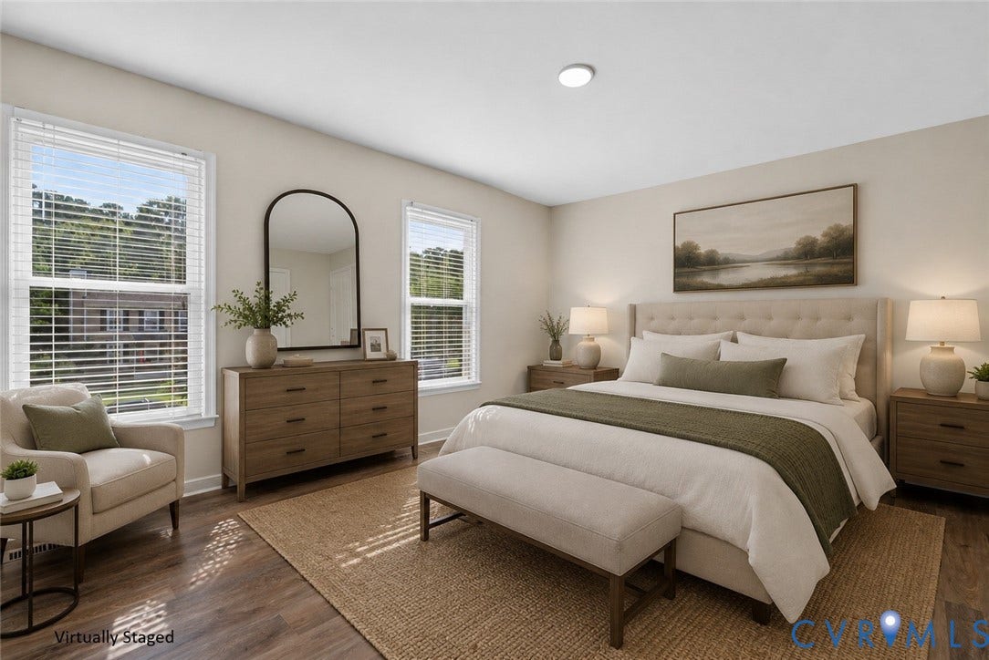 2020 Knotty Drive, Glen Allen, VA 23060 Primary Bedroom featuring wood-finish flooring, dual windows with plantation shutters, arched mirror above wood dresser, bedside nightstands with attached lighting, and landscape artwork above the headboard