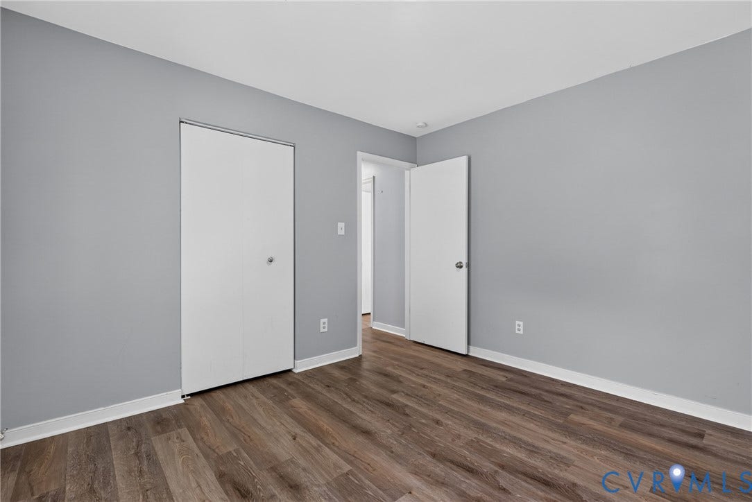 2020 Knotty Drive, Glen Allen, VA 23060 Bright corner bedroom featuring pristine white panel doors, neutral gray walls, and warm wood-finish flooring throughout