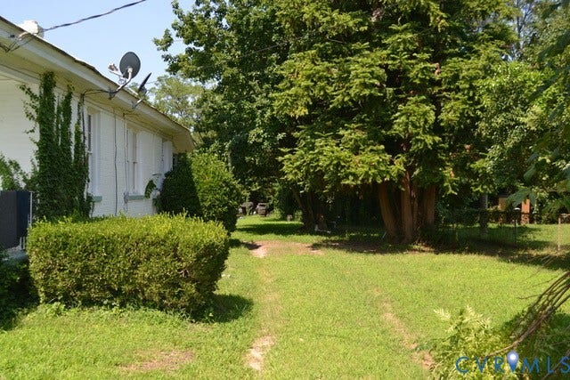 White exterior siding with vine accents, manicured hedges, and mature trees