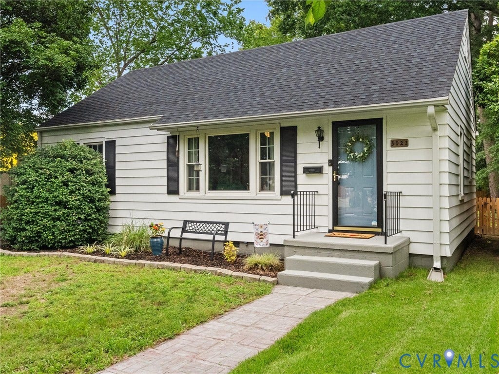 5023 E Seminary Avenue, Richmond, VA 23227 White siding exterior featuring a dark asphalt shingle roof and a light blue entry door