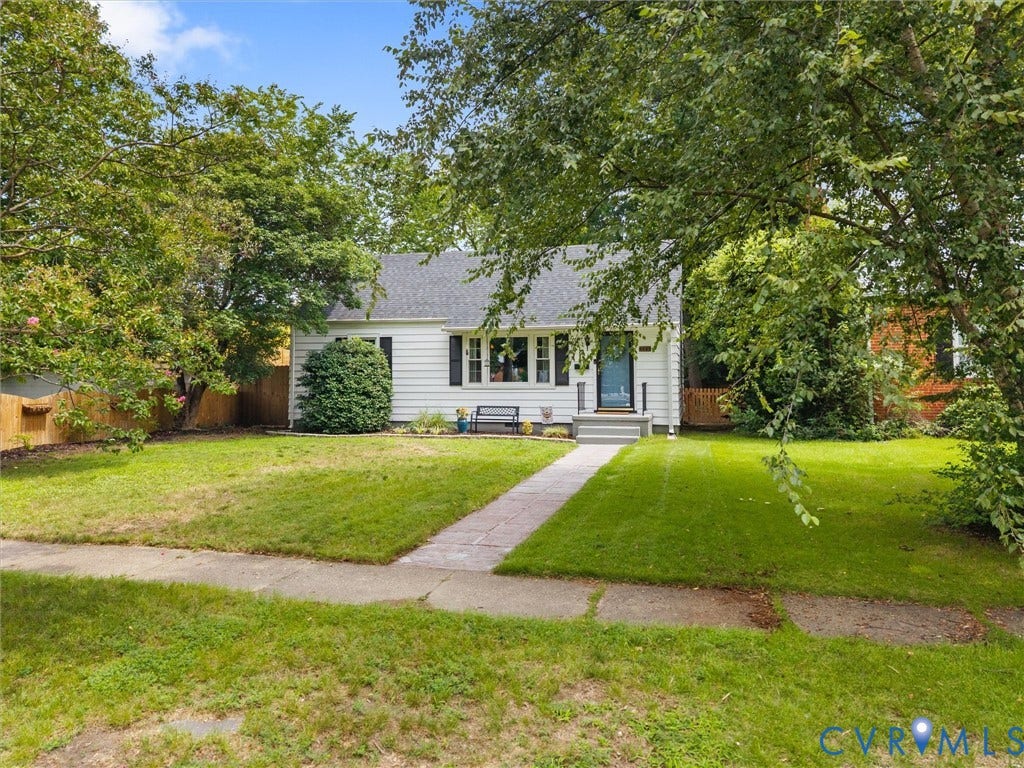 5023 E Seminary Avenue, Richmond, VA 23227 Charming cottage-style home featuring a brick front walkway, expansive manicured lawn bordered by mature shade trees, and a welcoming front entrance with covered porch and multi-pane windows