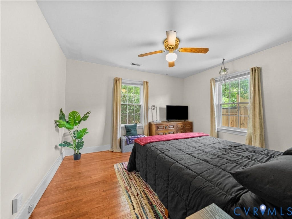 5023 E Seminary Avenue, Richmond, VA 23227 Bright room featuring wood-finish flooring, two large windows, a ceiling fan with integrated lighting, and white baseboards