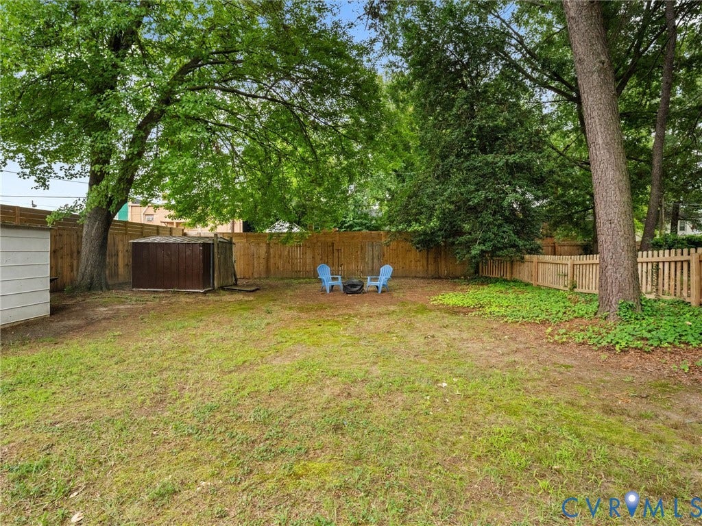 5023 E Seminary Avenue, Richmond, VA 23227 Spacious backyard oasis featuring mature shade trees, level lawn, wooden privacy fencing, and a detached garage