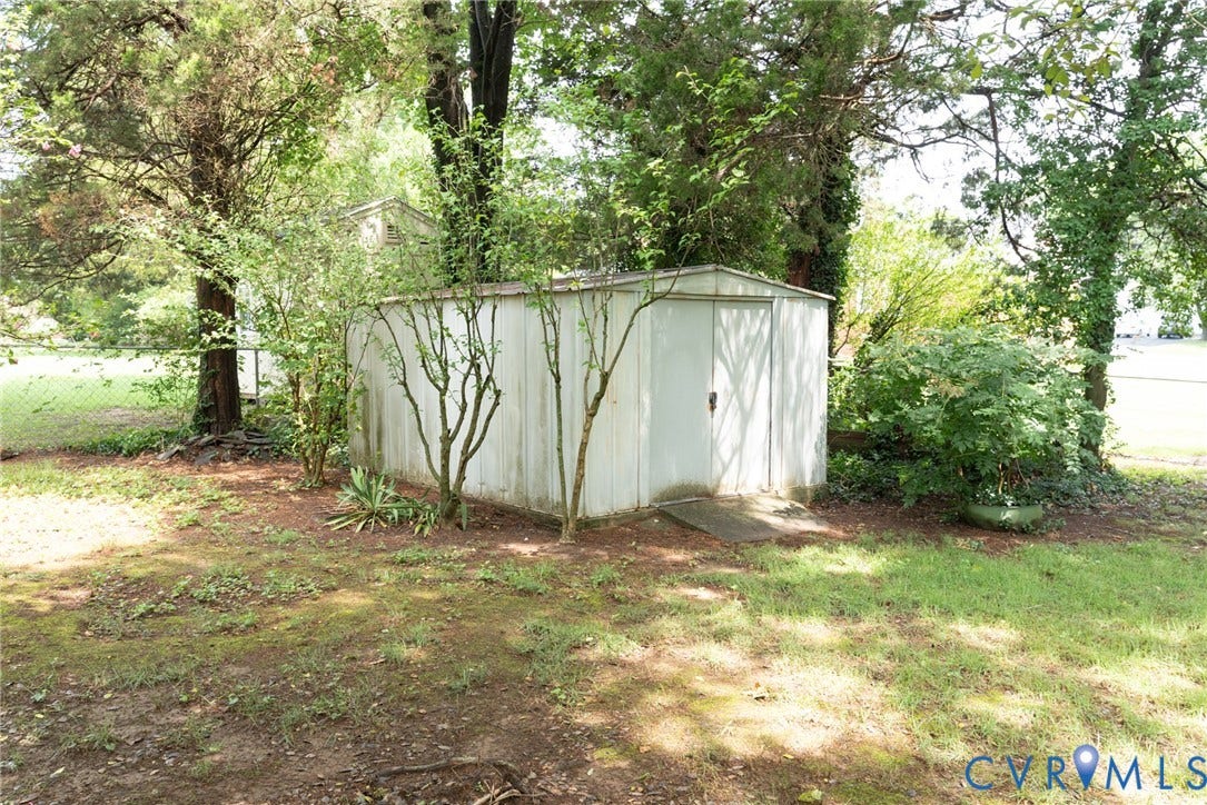 2519 Woodmont Drive, Woodmont, Chesterfield, VA 23235 White metal utility shed with a single door, surrounded by mature trees and varied foliage