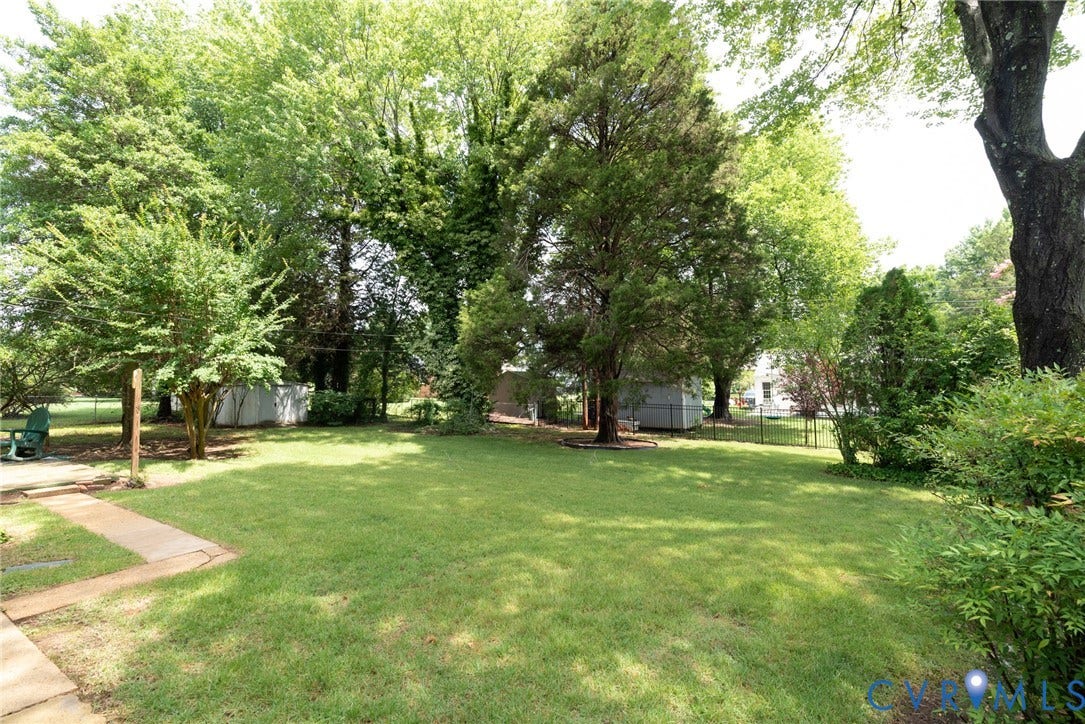 2519 Woodmont Drive, Woodmont, Chesterfield, VA 23235 Expansive green lawn surrounded by mature trees, a small storage shed, and partial fencing