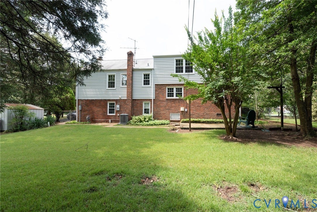 2519 Woodmont Drive, Woodmont, Chesterfield, VA 23235 Expansive grassy backyard featuring a brick and siding exterior, mature trees, a storage shed, and a paved patio area