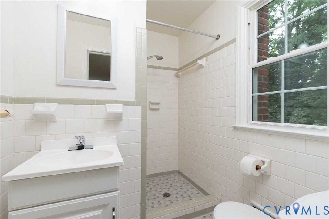 2519 Woodmont Drive, Woodmont, Chesterfield, VA 23235 Bathroom featuring white tile walls, a white vanity with an integrated sink, a tiled shower with a mosaic floor, and a window with white trim